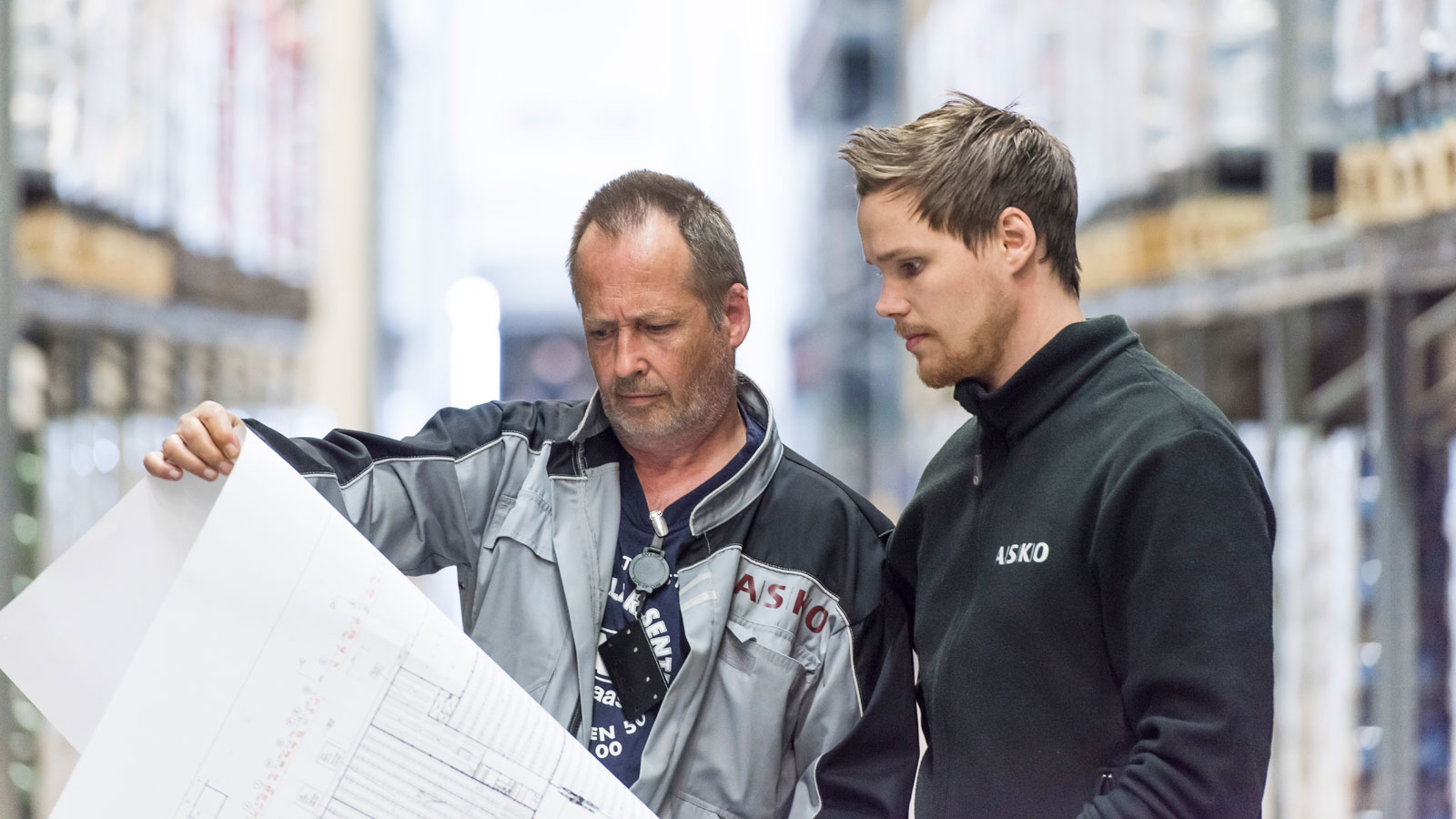 To ansatte på lageret som ser på et papir
