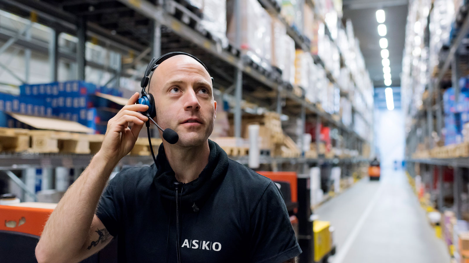 ASKO-ansatt på lageret med stemmeplukk på øret