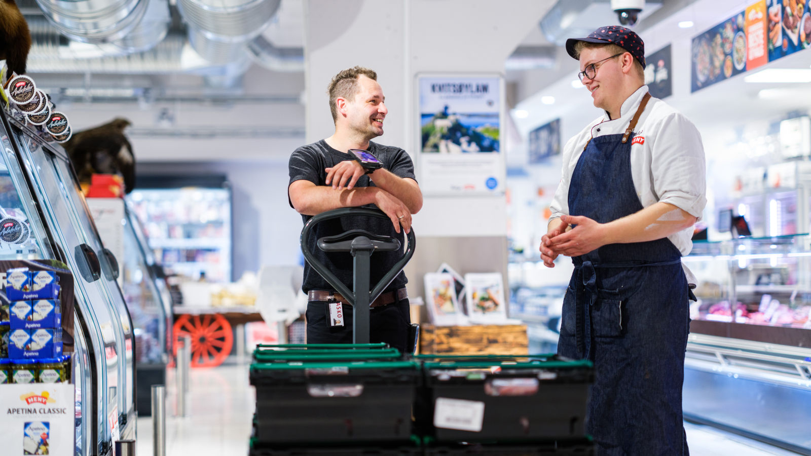 Meny ansatt og ASKO sjåfør snakker sammen i butikken