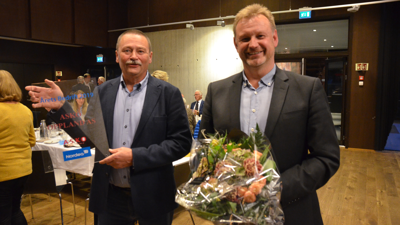 ASKO-direktør Asbjørn Vedvik Jensen (t.v.) og økonomisjef Olav Tronrud i ASKO OPPLAND med blomster og plaketten for Årets bedrift 2019