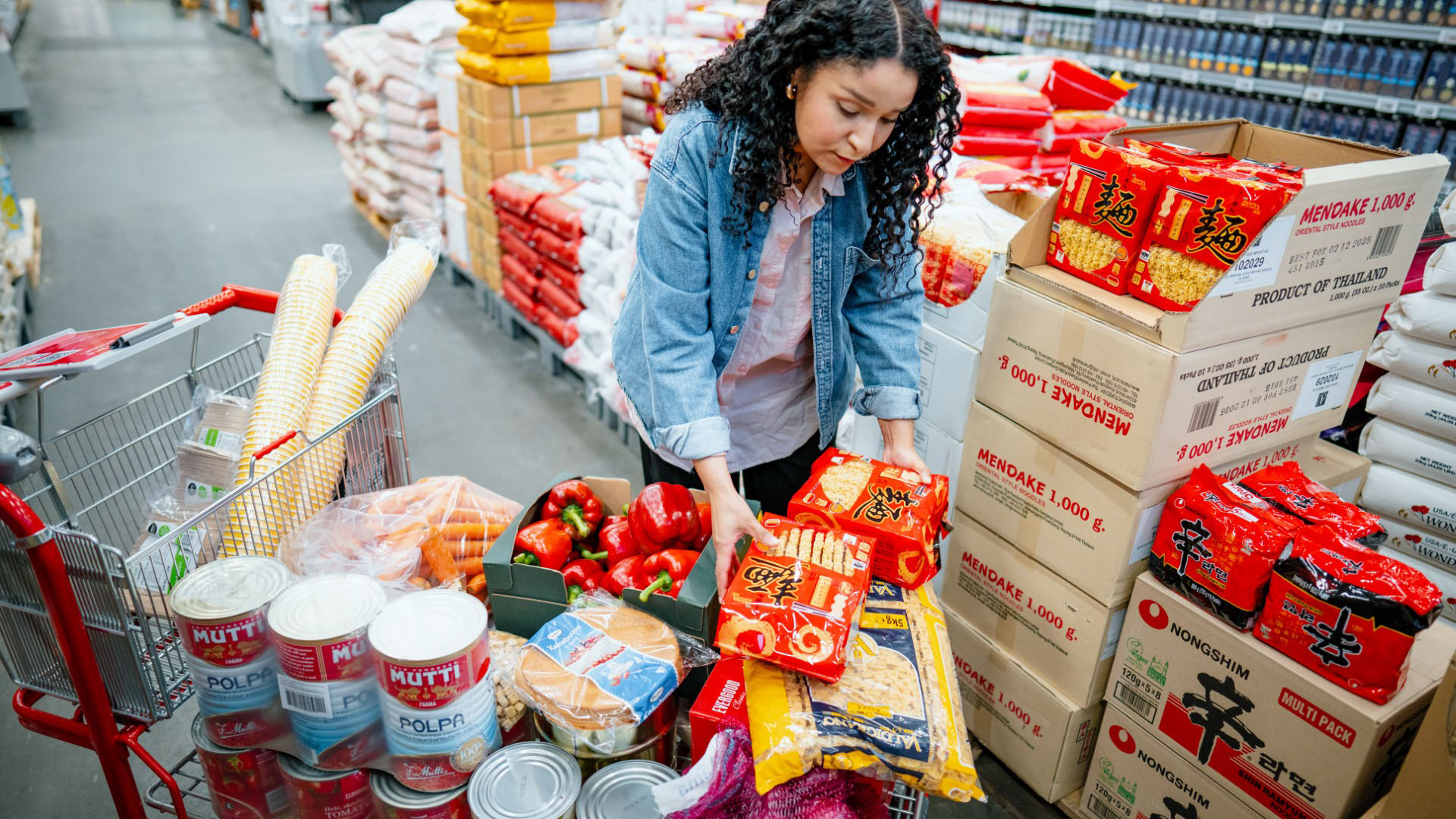 Bilde av en dame med en stor handlekurv som handler inne på Storcash.